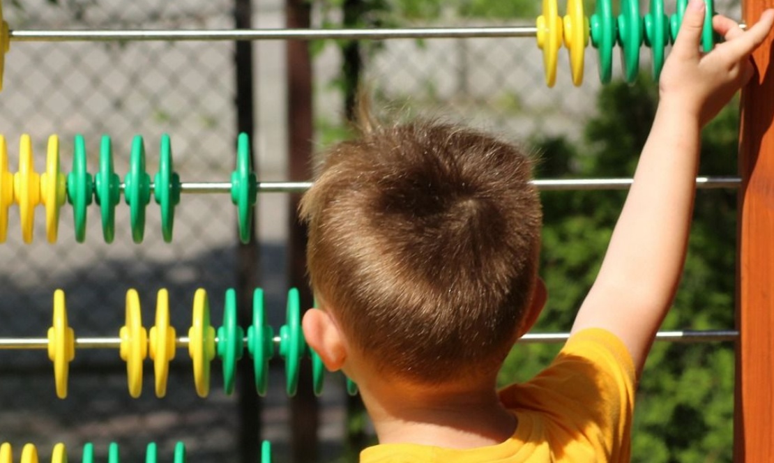 Image of infant school-age child and giant abacus